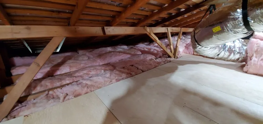 An attic insulated with pink fiberglass insulation and equipped with ductwork by InsulationGuruInc.dbaHVACGuru in San Jose.